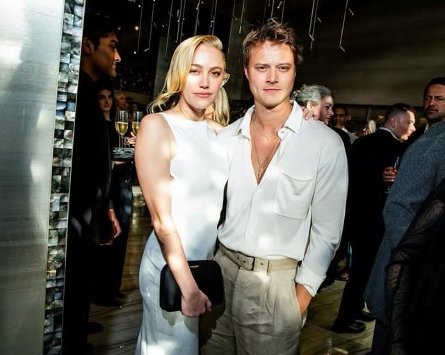 Two guests dressed in white posing together at an evening event